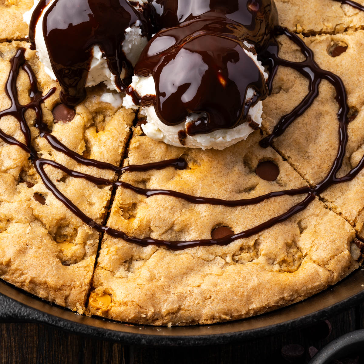 A skillet cookie topped with ice cream and chocolate sauce.