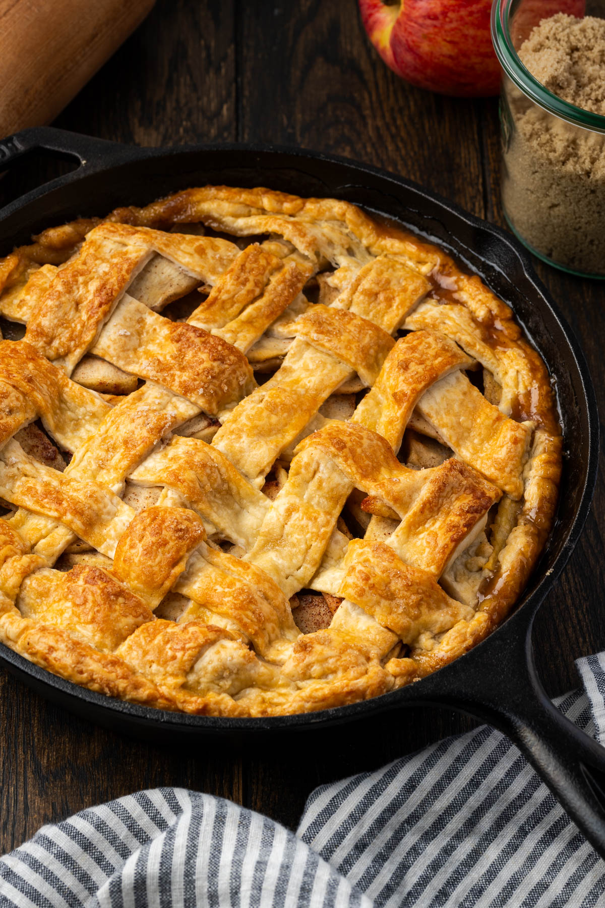 Cast iron apple pie with a criss cross patterned top crust on the table.