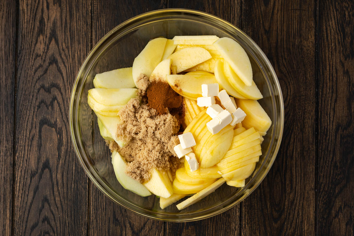 Apple pie ingredient added to the apples in a bowl.