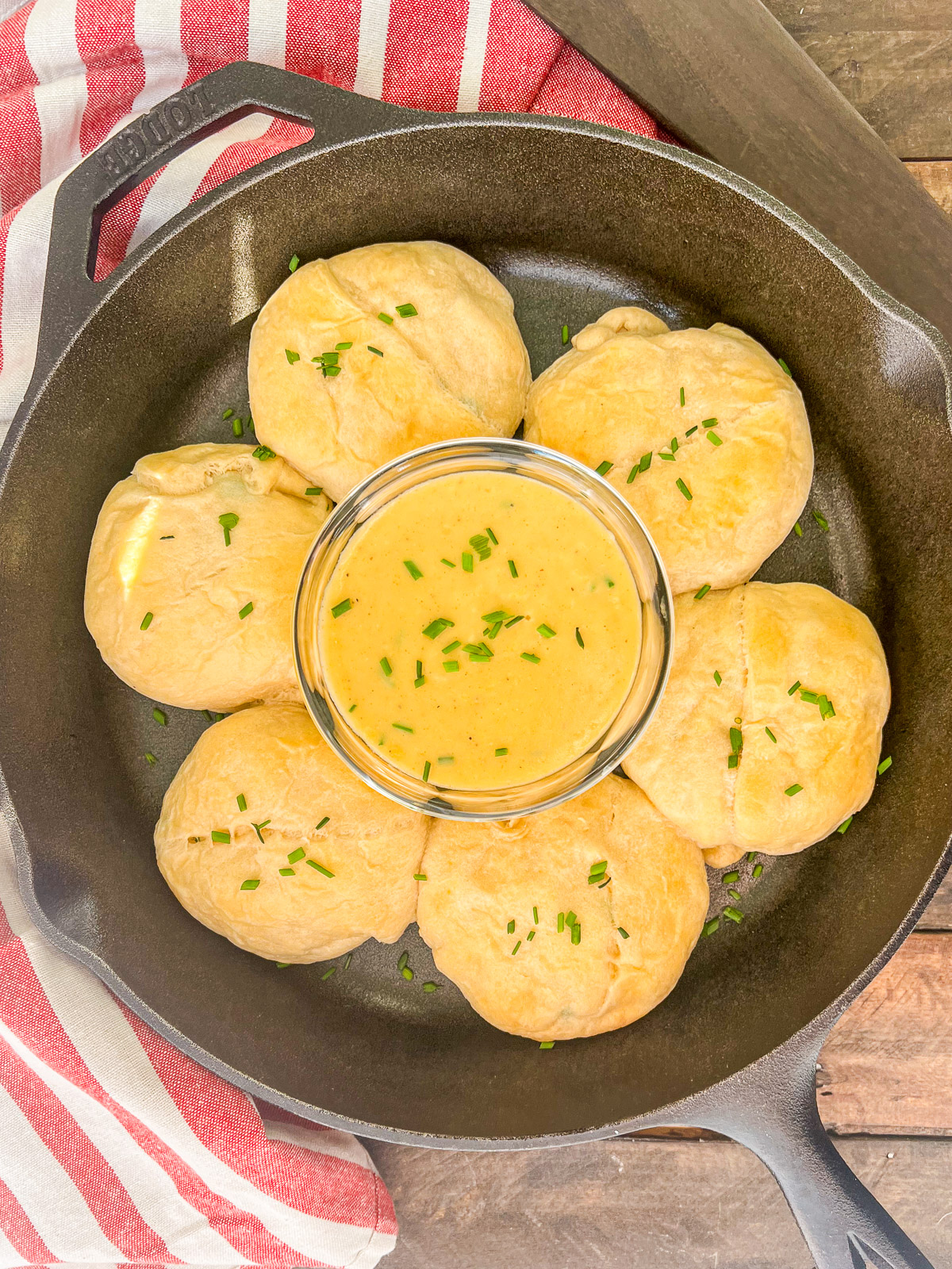 Chicken pillows in a cast iron skillet with a bowl of gravy in the center.