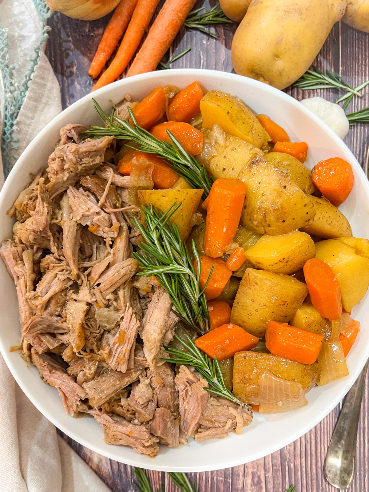 Close up of the pork roast with onions, carrots, and potatoes on a plate ready to serve.