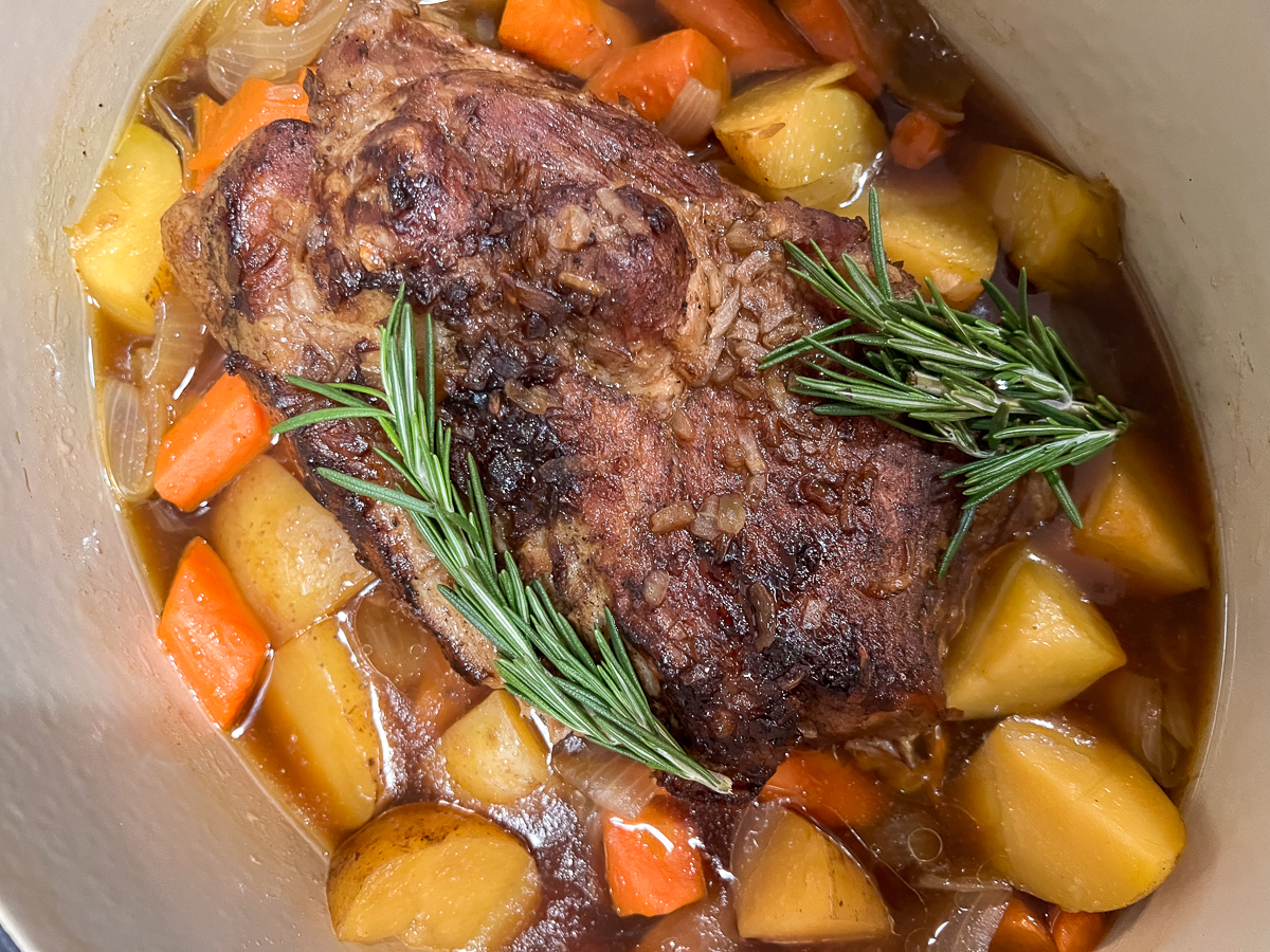 Close up of the pork roast with onions, carrots, and potatoes, in the au jus.
