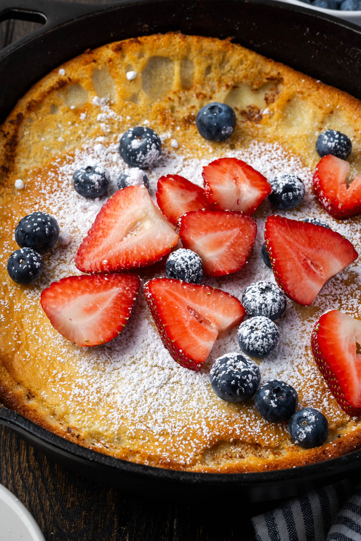 A cast iron dutch baby in a skillet topped with fresh fruit.