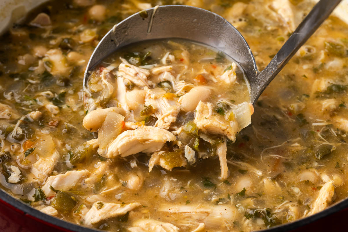 A ladle lifting up a spoonful of white chicken chili.
