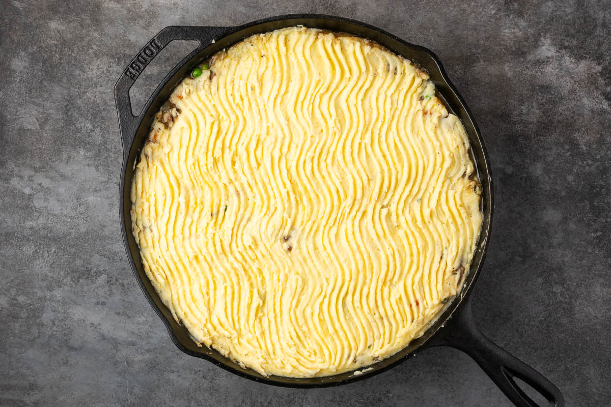 Mashed potatoes spread on top of the beef mixture.