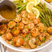 Garlic lemon butter sauce being poured over scallops.