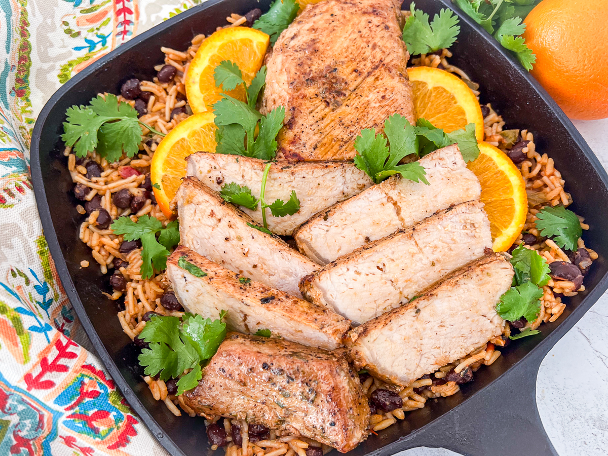 Chipotle orange pork tenderloin in a bed of rice and beans in a cast iron skillet.