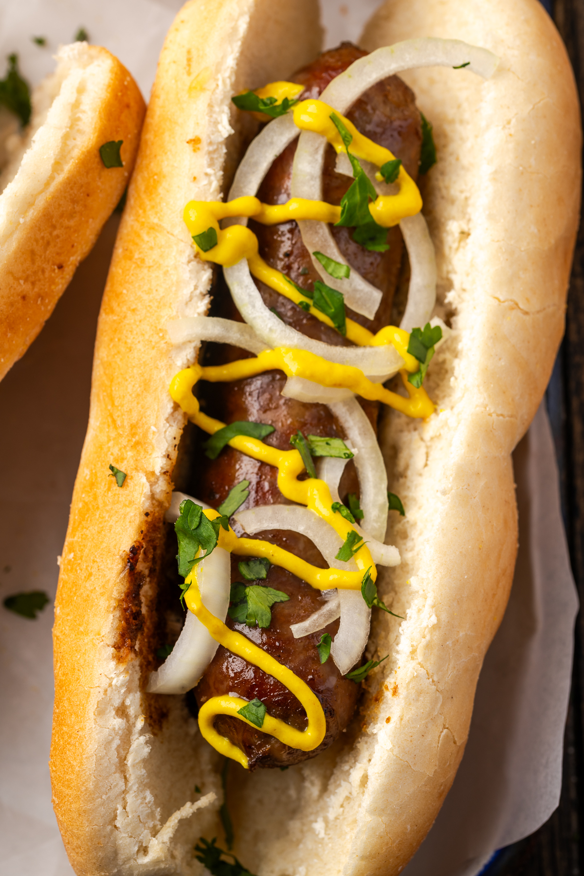 A close up of a beer brat on a bun with toppings.