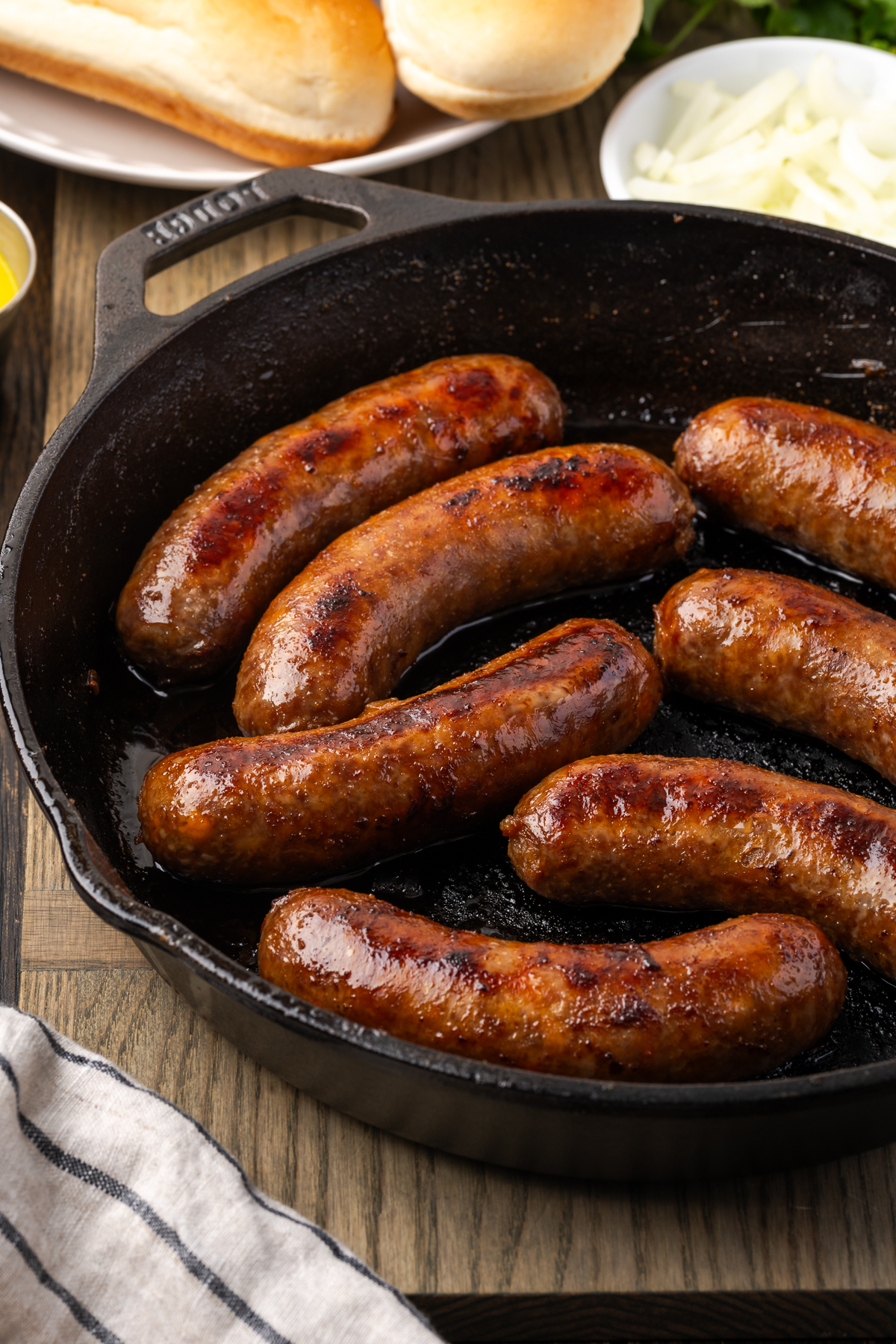 Beer brats cooking in a skillet.