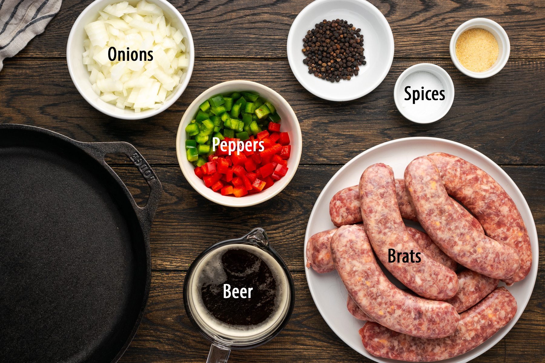 Ingredients to make beer brats on a wooden surface with text labels identifying each one.