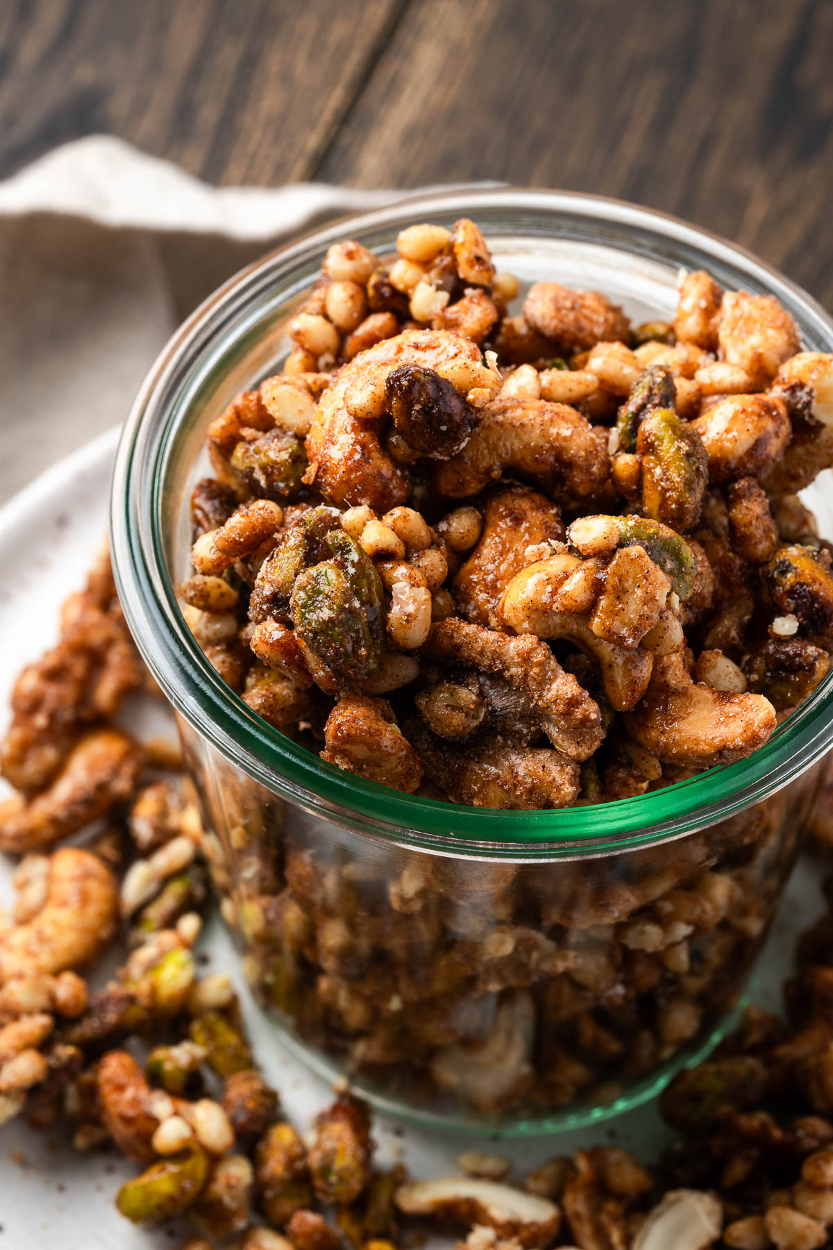 A jar of cinnamon nuts on a plate with more scattered around it.