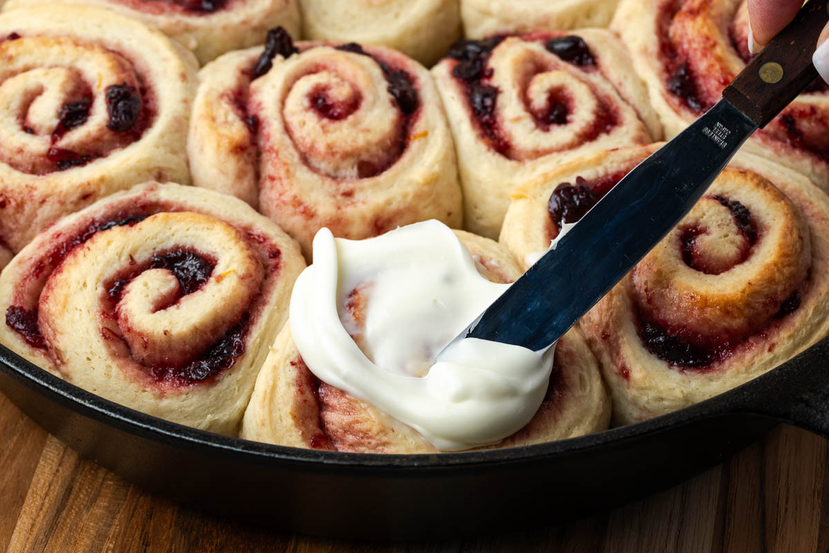 Adding the frosting to the cherry rolls.