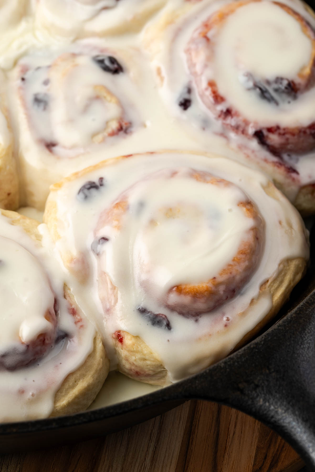 Cherry rolls with icing in a cast iron skillet.