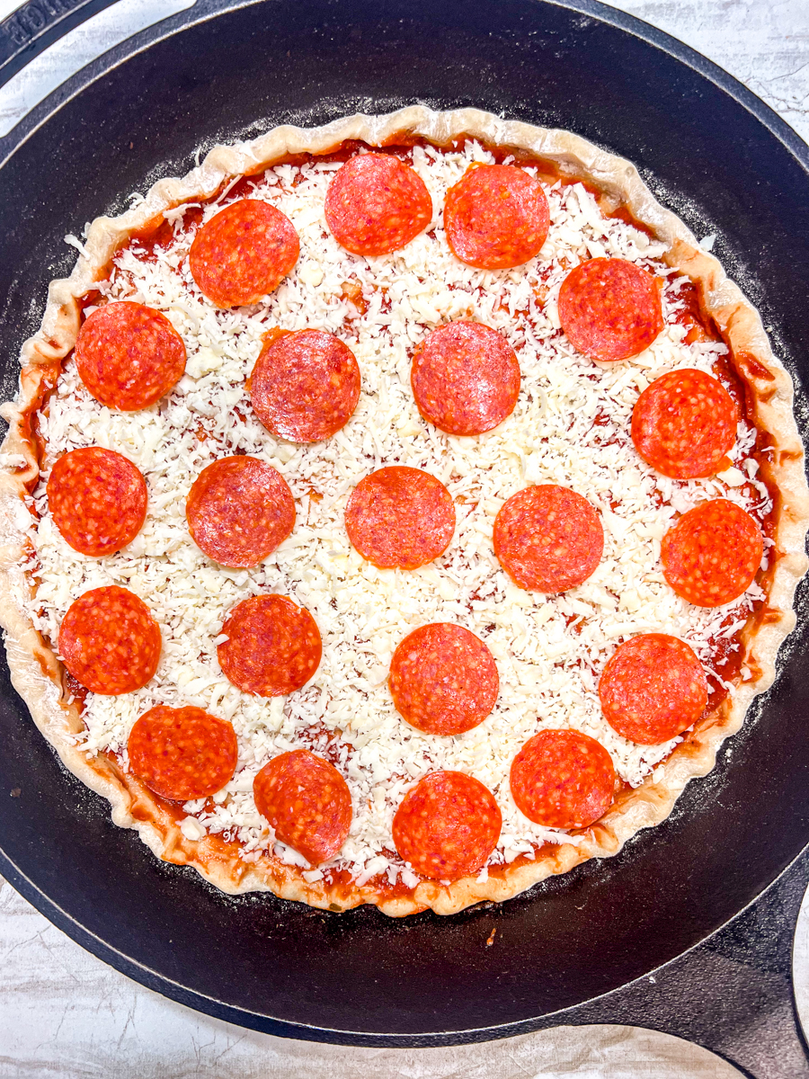 Pepperoni pizza on a skillet ready to bake.