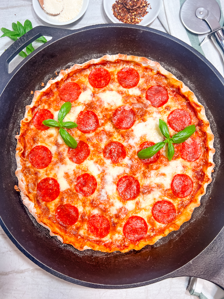 A cast iron pizza garnished with fresh basil.