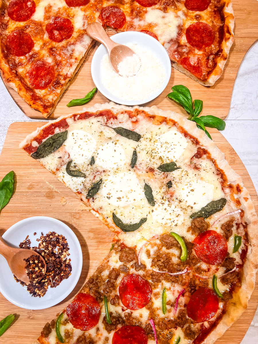 Pizzas with a variety of toppings on a board with slices missing.