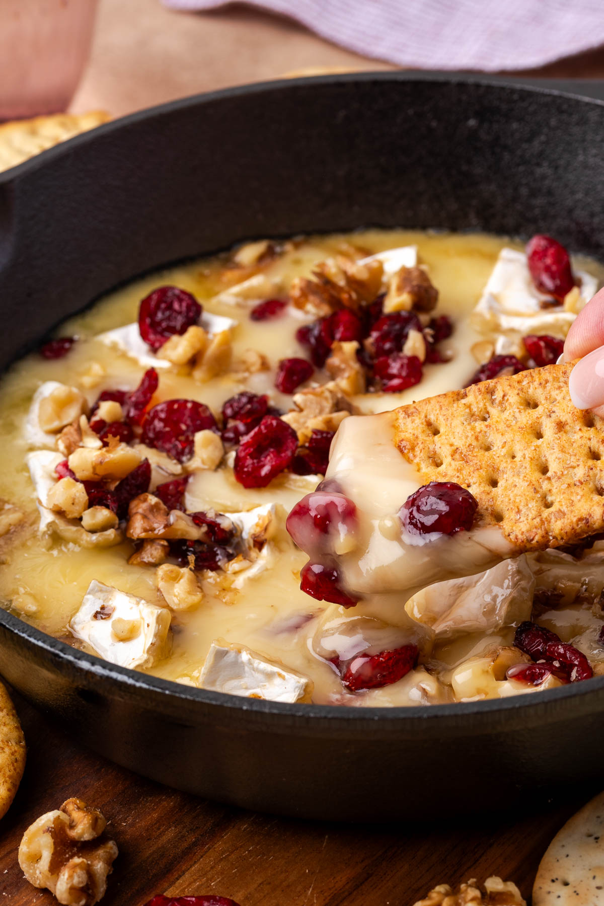 A cracker scooping up a bite of cranberry baked brie.