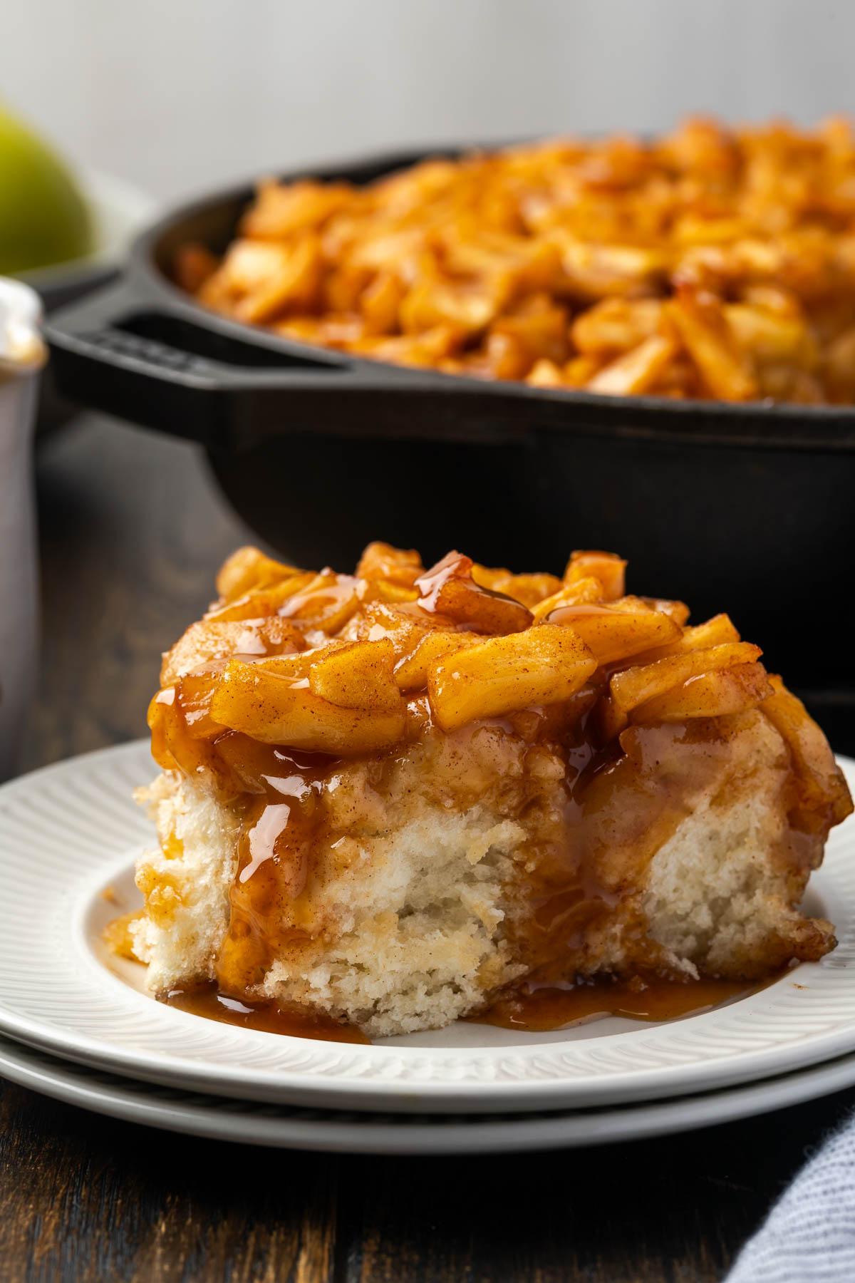 A plate of baked caramel apple pizza in front of a skillet of more.