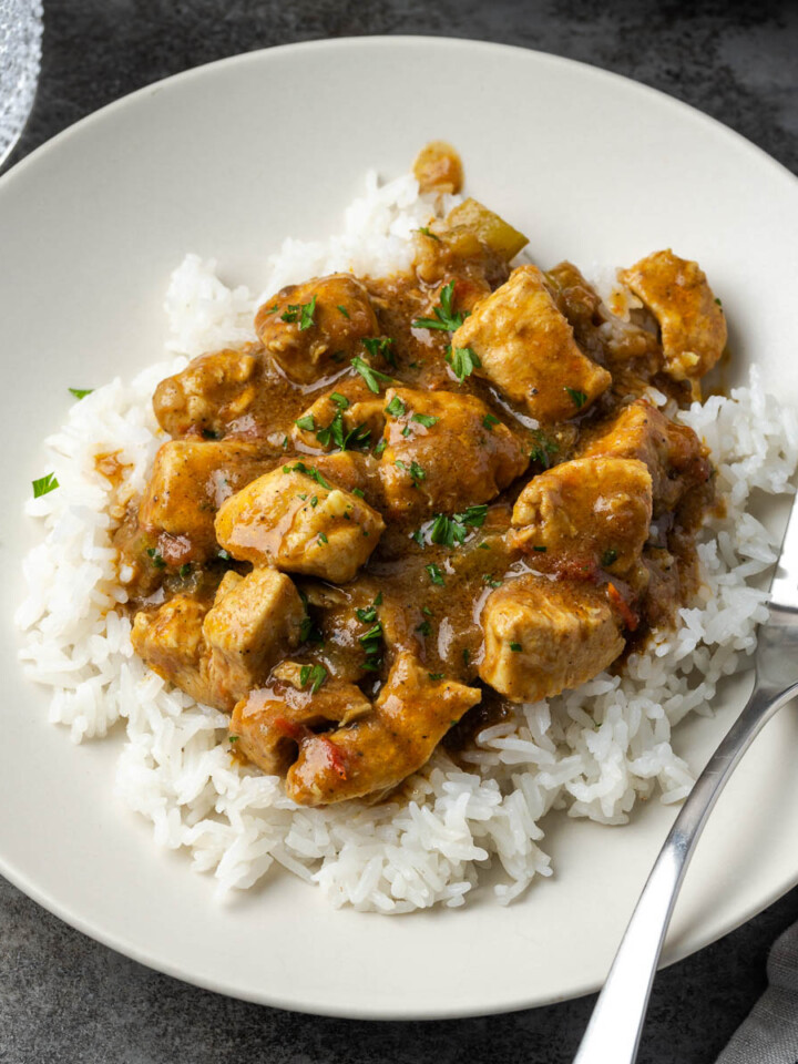 Easy chicken curry over rice on a white plate with a fork resting to the side.