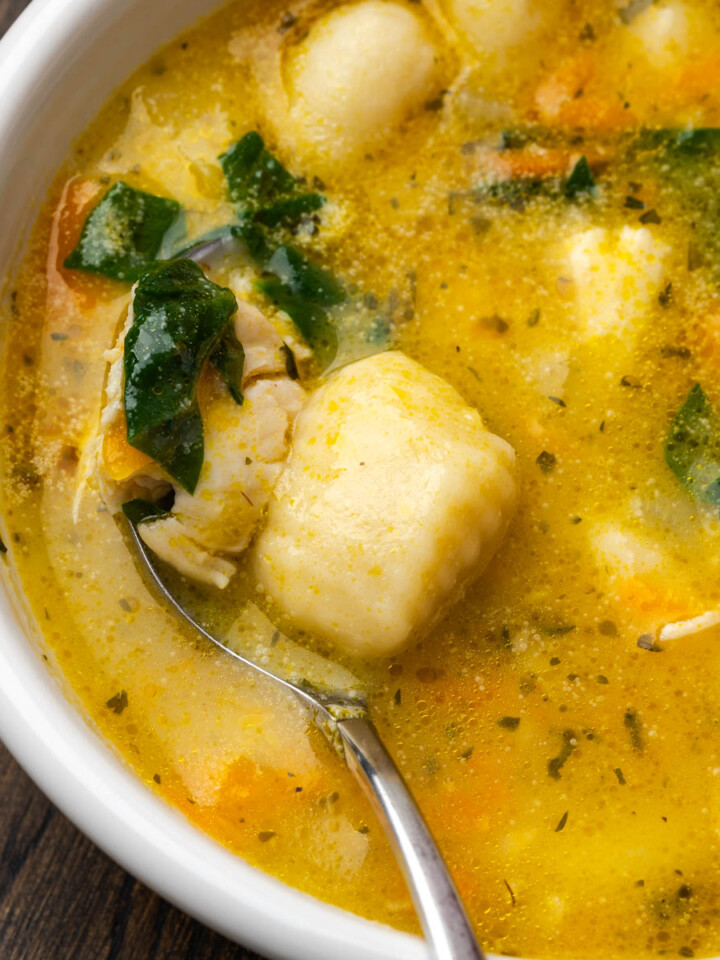 A bowl of creamy chicken gnocchi soup with a spoon in the bowl.