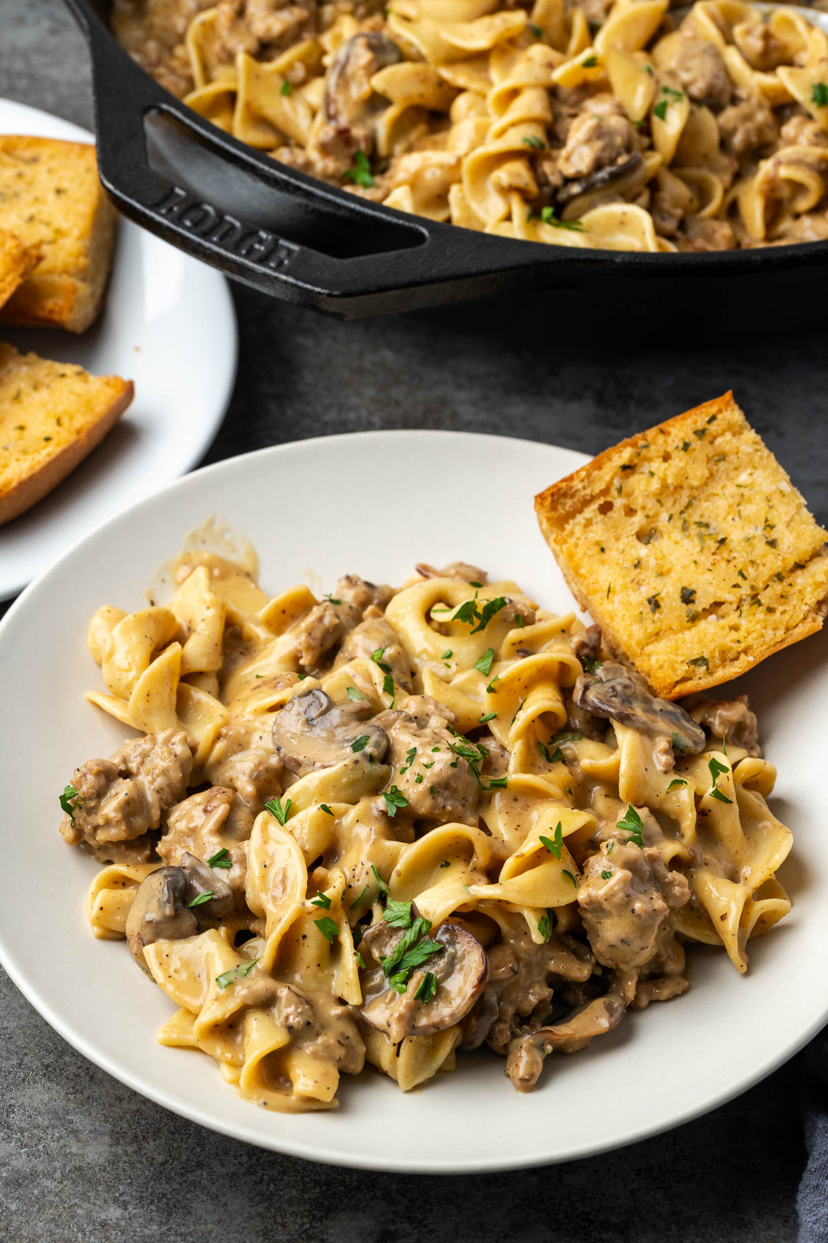 Ground turkey stroganoff on a plate with a skillet of more in the background.