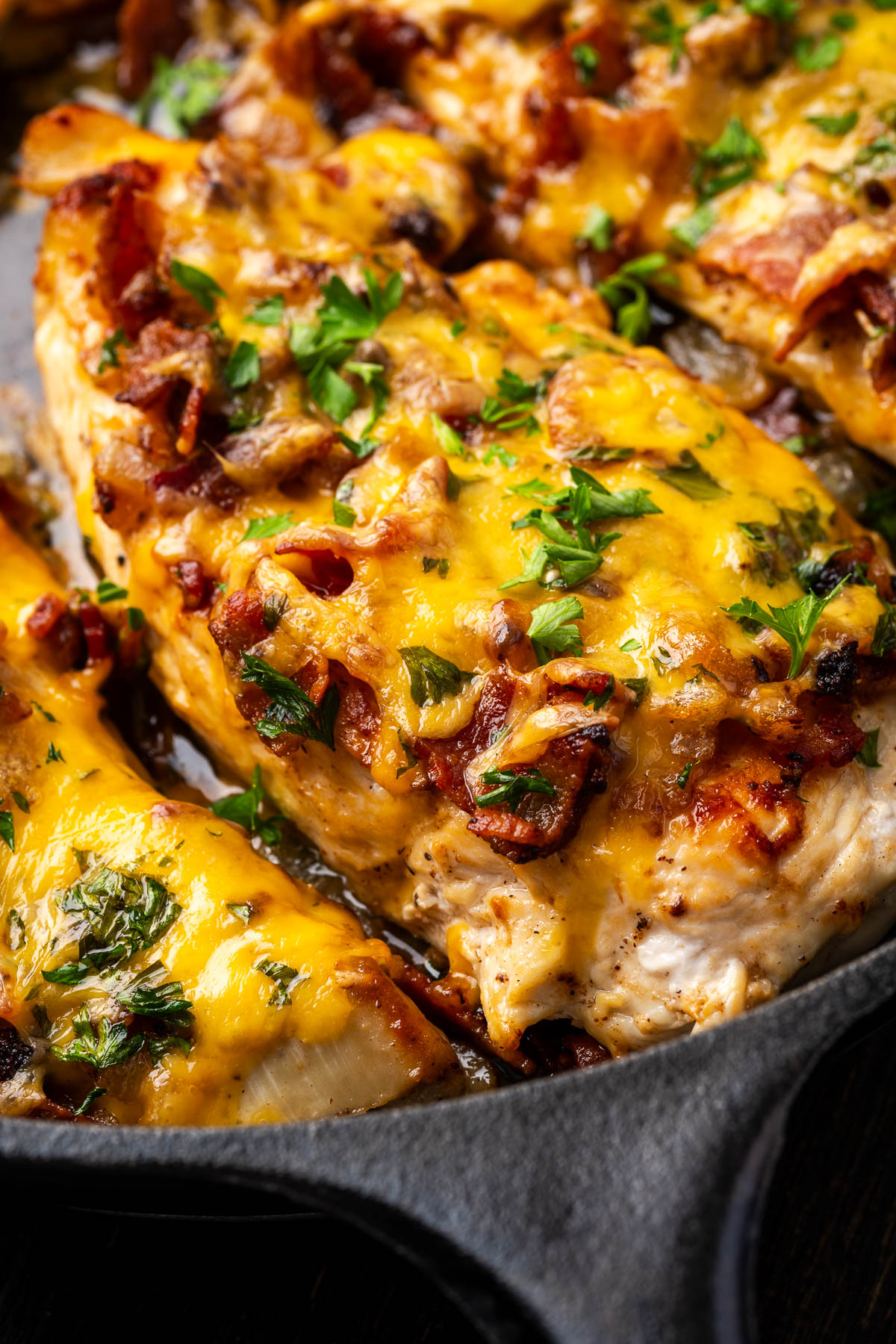 Cheesy bacon chicken in a cast iron skillet garnished with green onion.