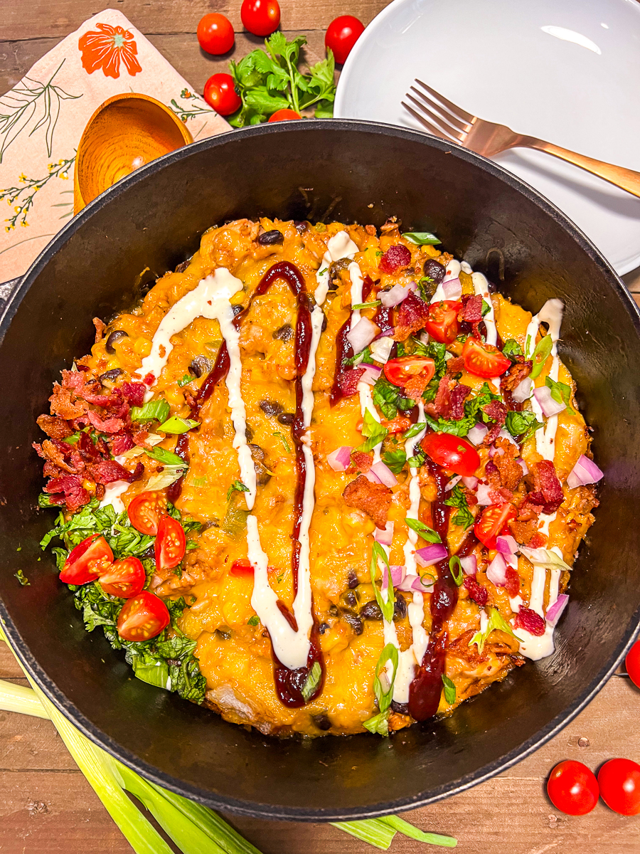 Barbecue Chicken and Rice in a dutch oven topped with bacon, cilantro, green onions, tomatoes, red onion, bbq sauce, and ranch dressing,
