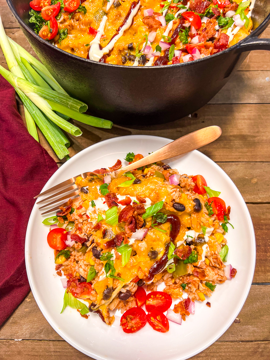 BBQ Chicken and rice served on a white plate with the dutch oven in the background.