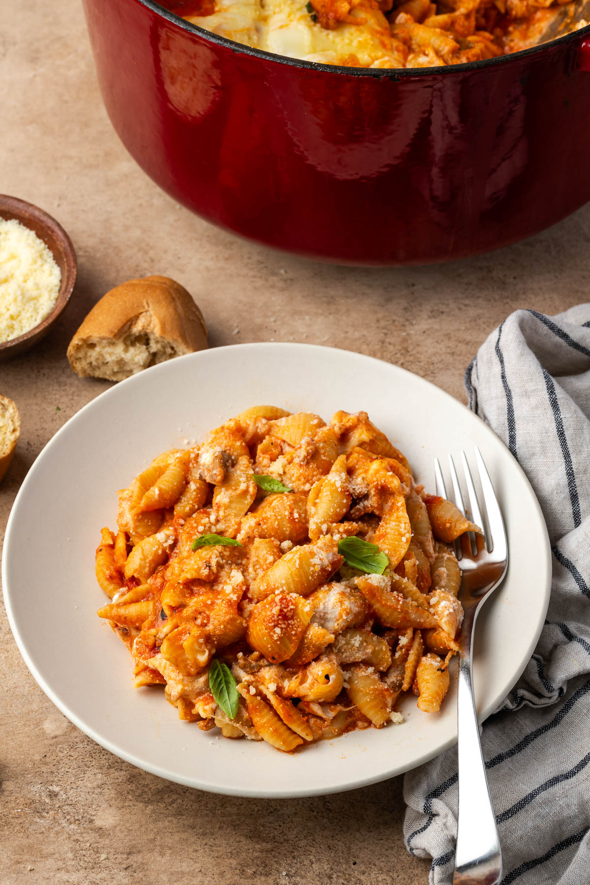 A plate with a serving of baked manicotti and more in the pot behind the plate.