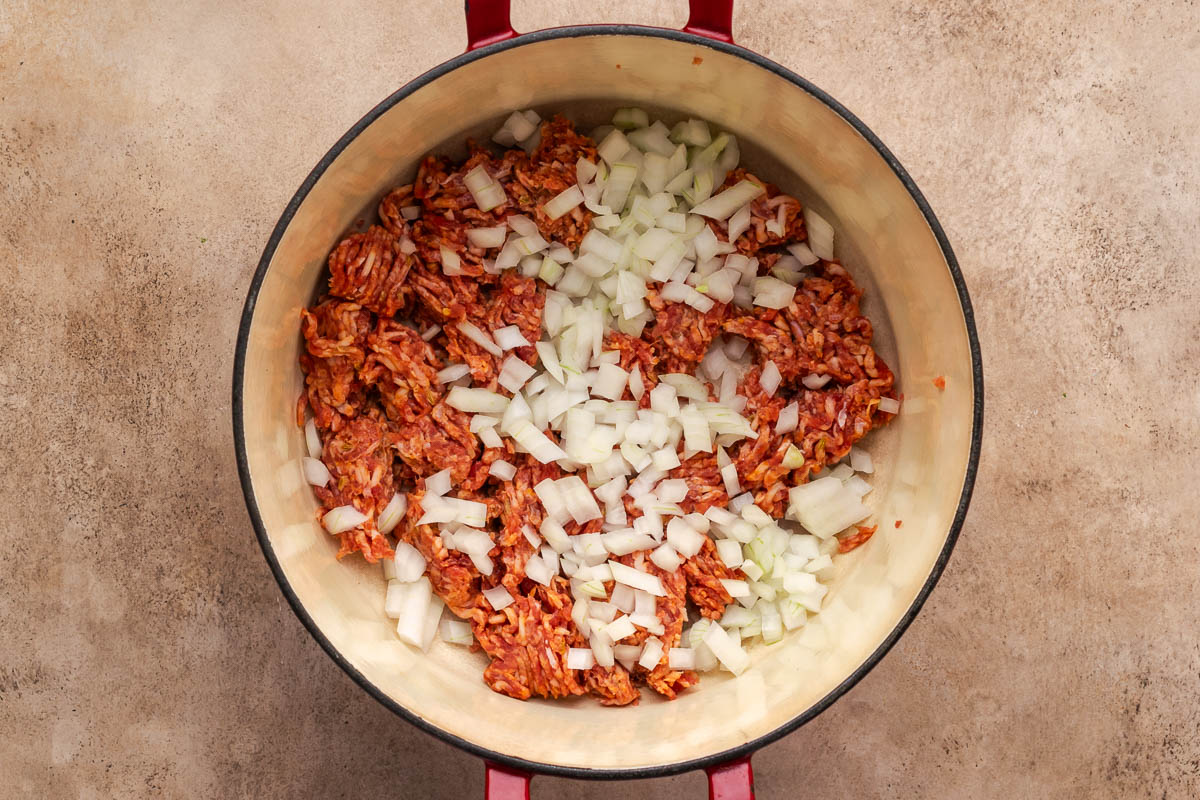 Onions and Italian sausage added to a Dutch oven to cook.