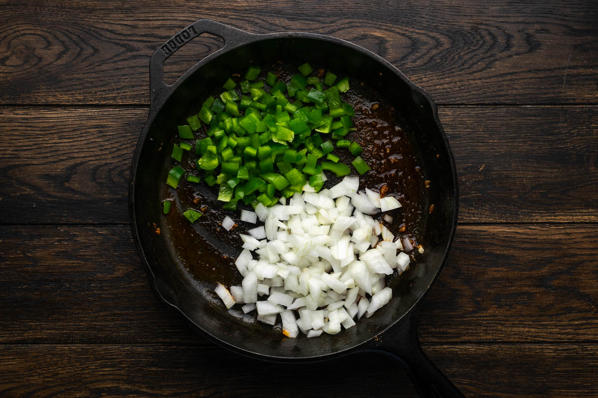 Onions and peppers cooking in a skillet.
