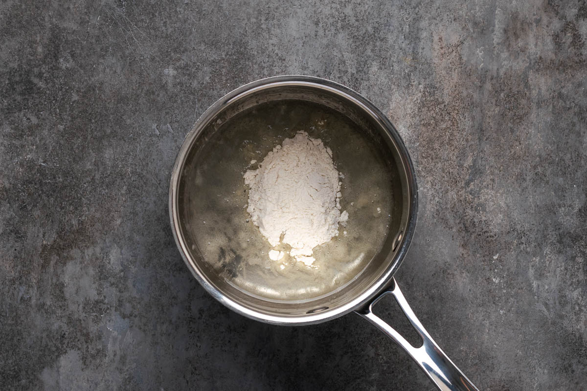 Adding the flour to the oil in a pot.