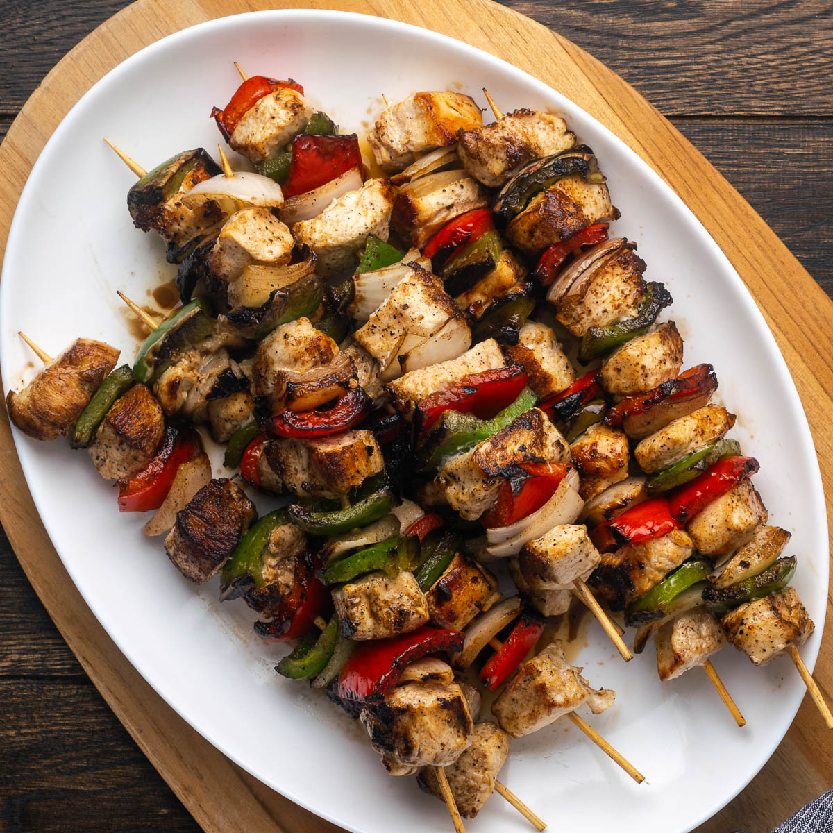 A pile of stovetop chicken kabobs on a white oval platter.