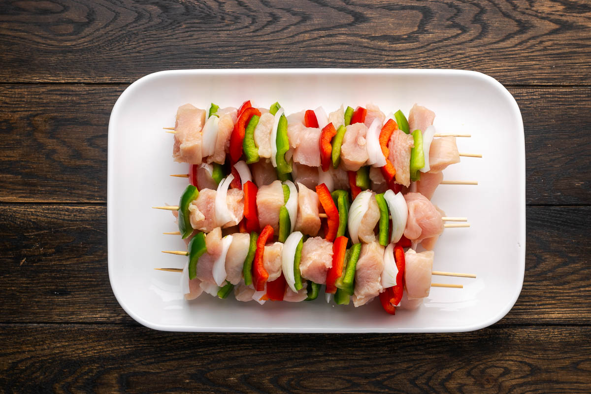 Kabobs prepped on a white plate.