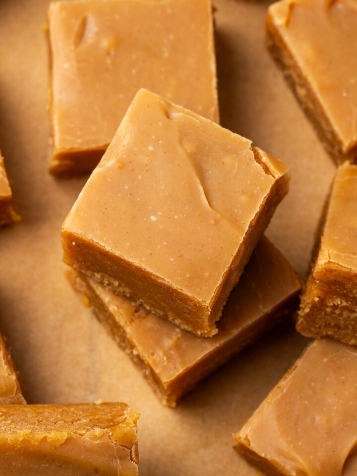 Pieces of peanut butter fudge on parchment with one piece stacked on top of another.