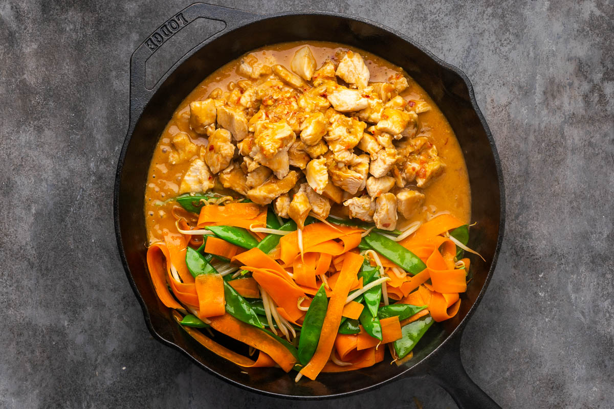 Chicken and sauce added to the skillet of cooked vegetables. 