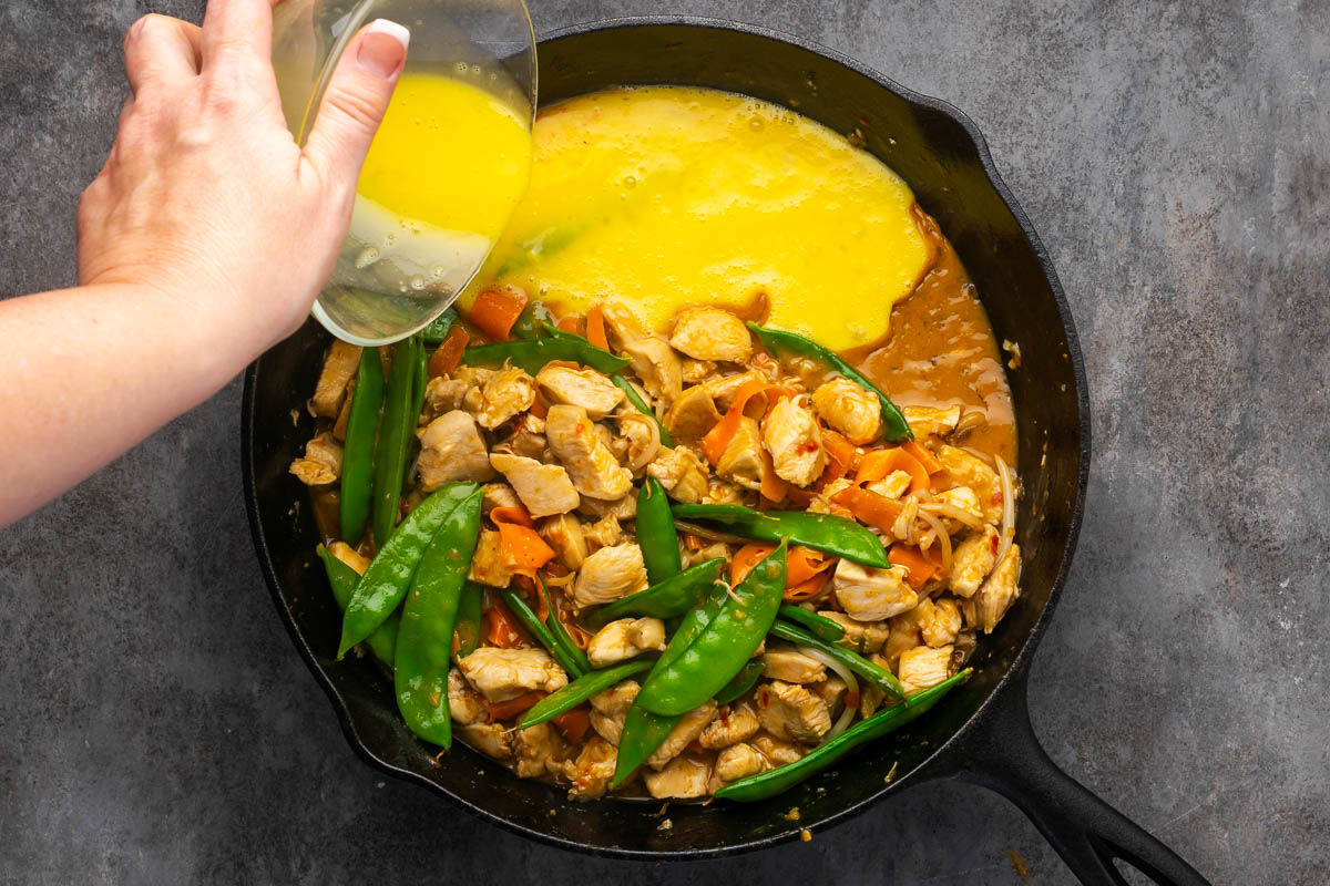 Adding the scrambled egg to the skillet. 