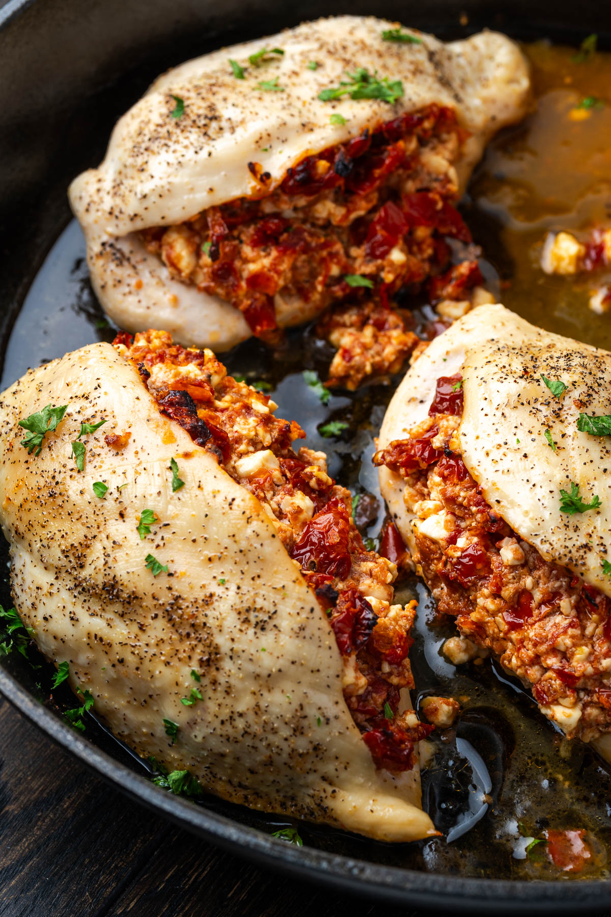 Sun dried tomato stuffed chicken breasts in a cast iron skillet.