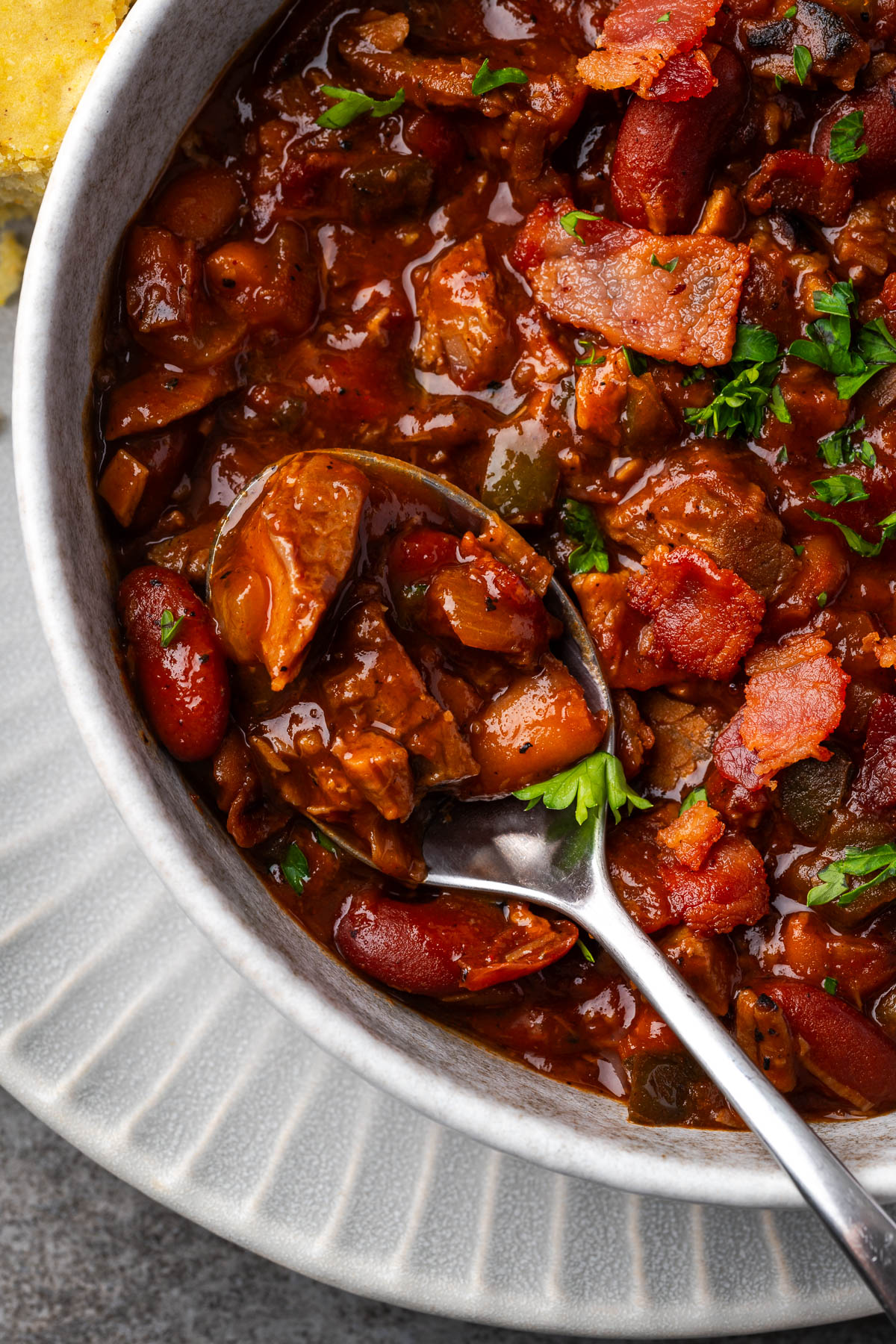 A bowl of brisket and beans with a spoon resting in the side. 