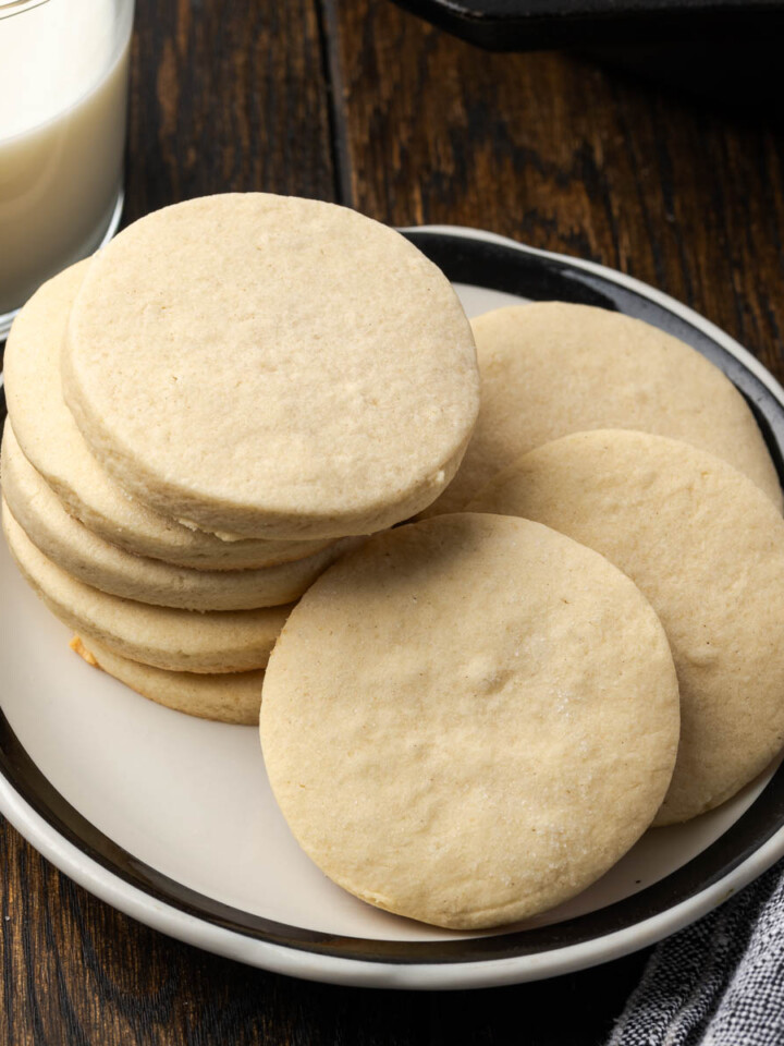 Skillet sugar cookies stacked on a plate and some leaning over.