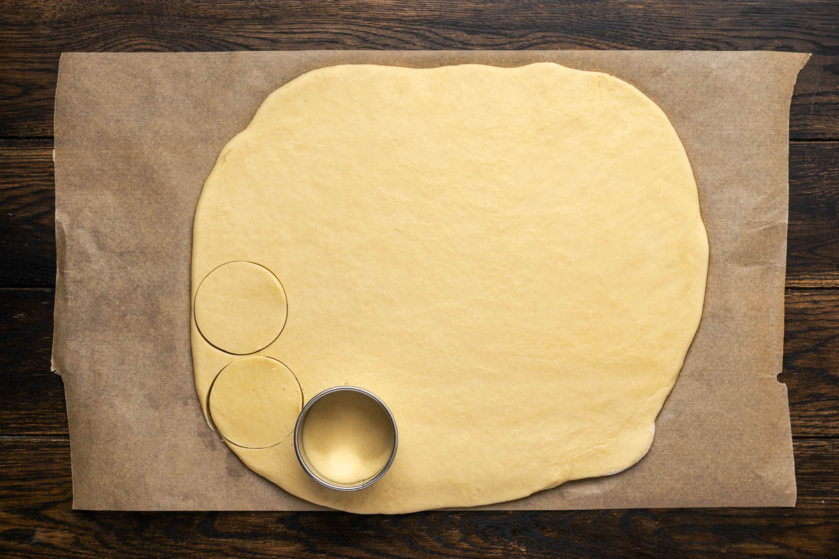 Cookie dough rolled out and cutting into circles with a cookie cutter.