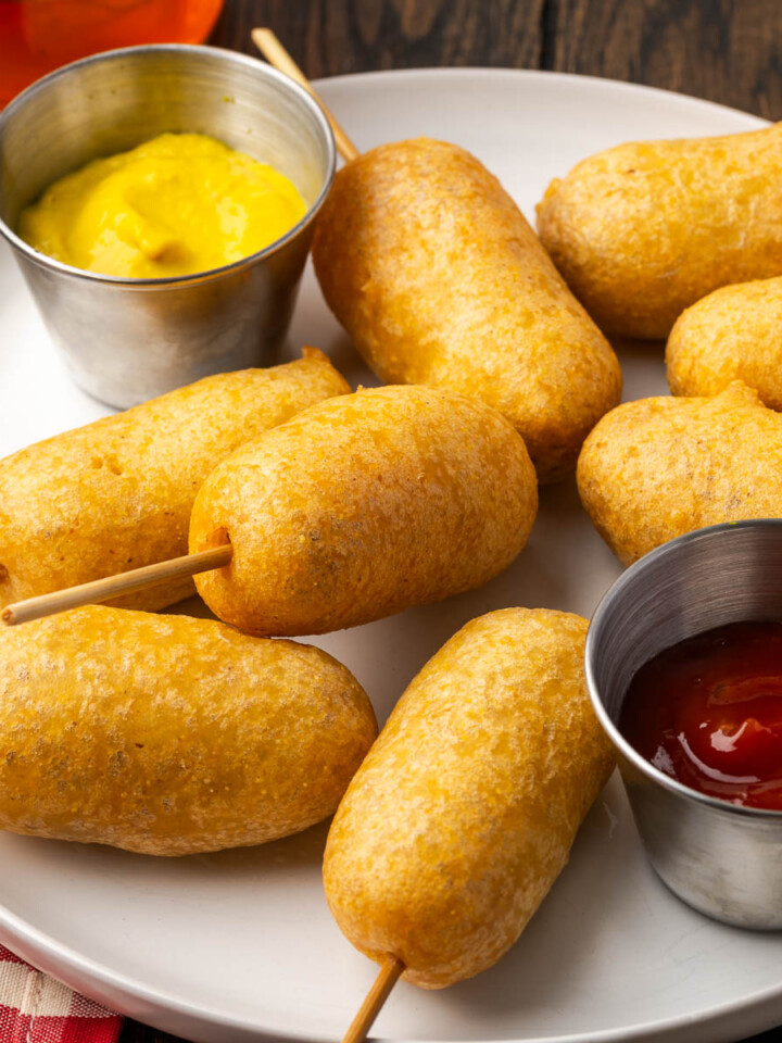 Homemade corn dogs on a plate with sauces.