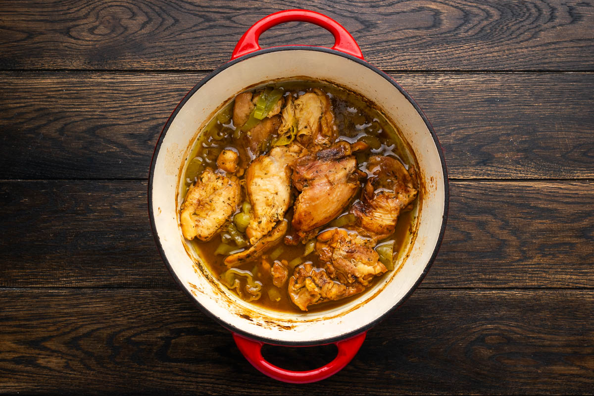 Chicken pieces cooking in a Dutch oven.
