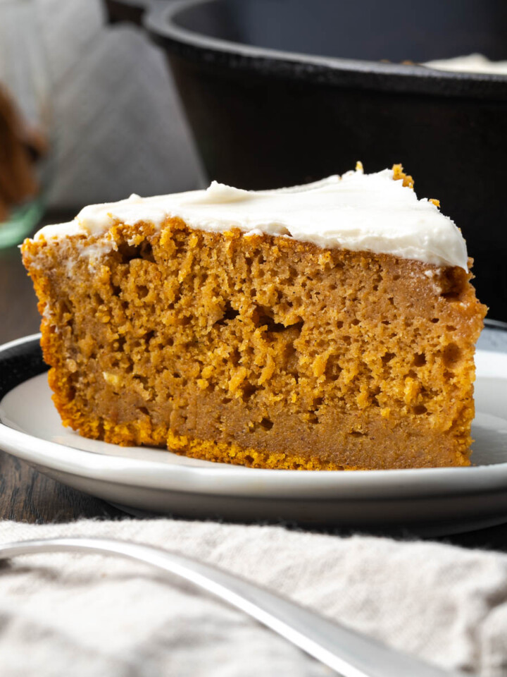 Pumpkin spice cake on a plate with a fork and napkin resting in the front.