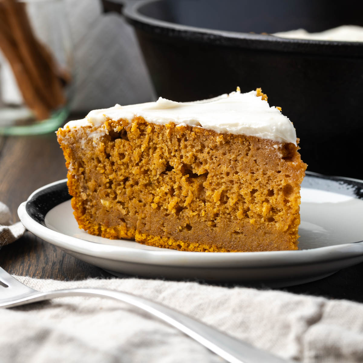 Pumpkin spice cake on a plate with a fork and napkin resting in the front.