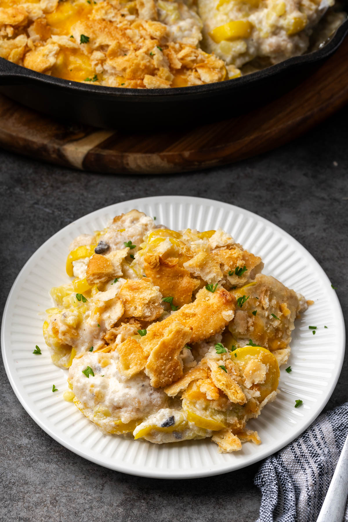 A plate of summer squash casserole with the dish of more in the background.