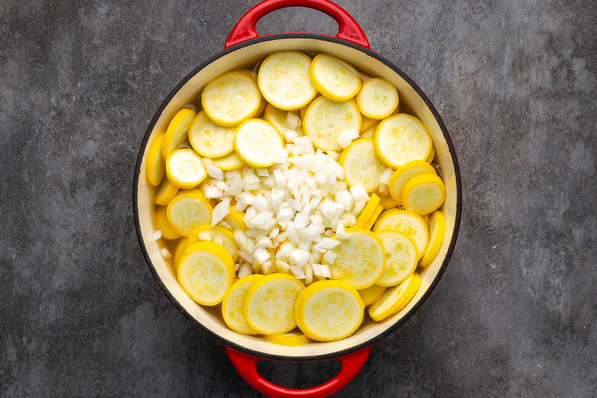 Squash and onions added to a large dutch oven.