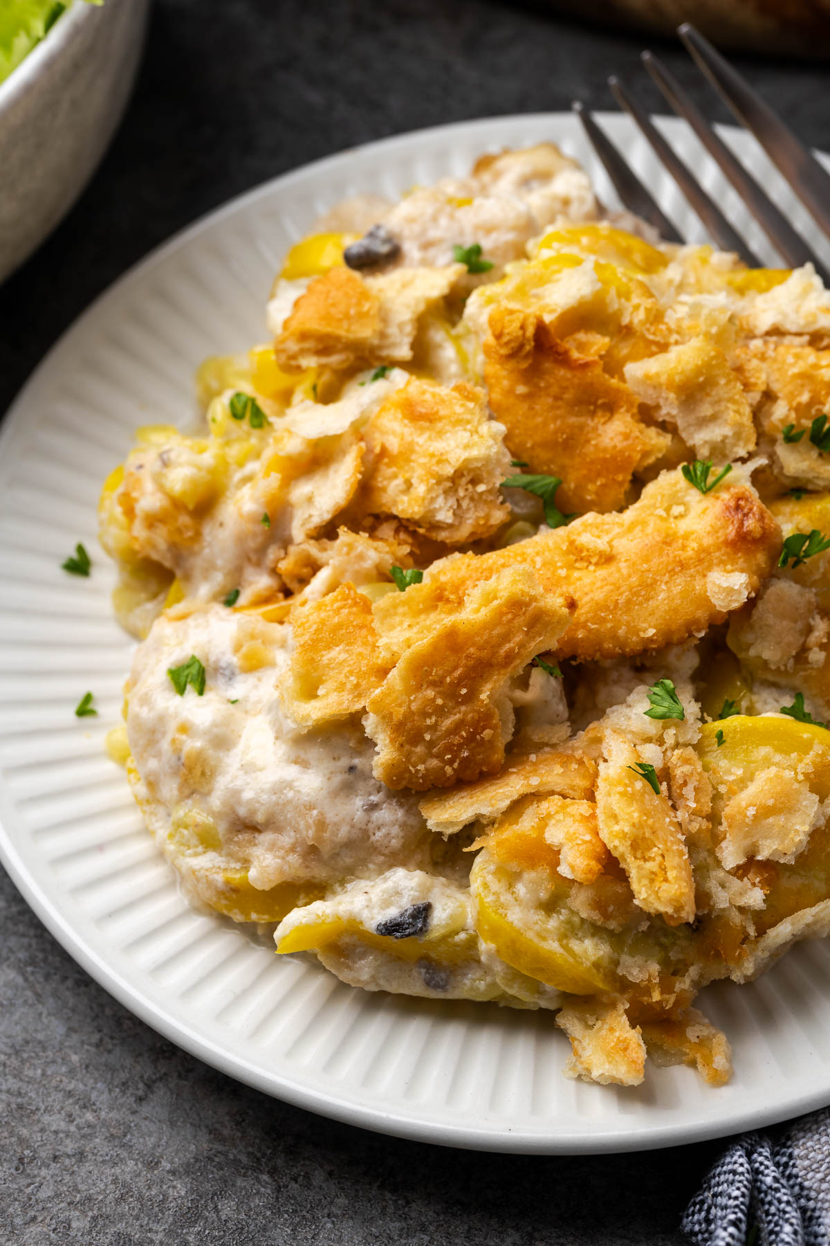A white plate topped with squash casserole and a fork resting to the side.