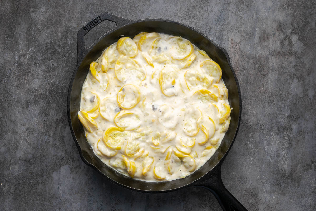 Squash casserole added to a cast iron skillet.