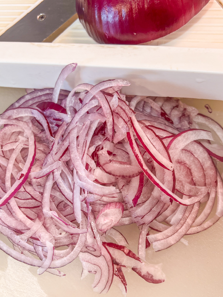 Red onions thinly sliced using a mandolin slicer.